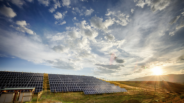 Solar Panels and Green Field Under Dramatic Sky at Sunset